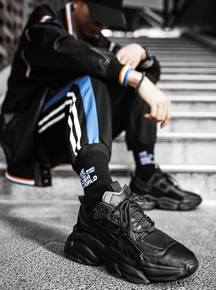 Black lace-up platform male sneakers on person sitting on steps, sporty and stylish with mesh design and EVA outsole.
