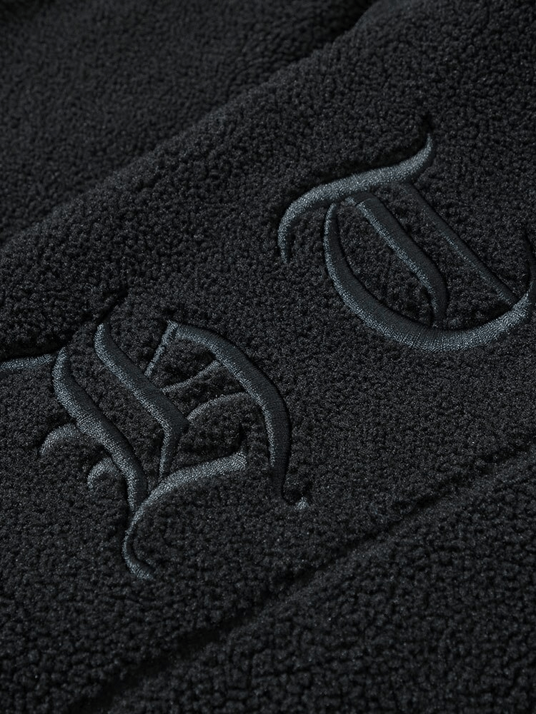 Close-up of embroidered letters on black fleece fabric from a hooded jacket