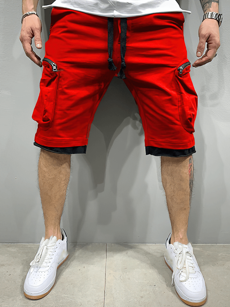 Fashion men's red cotton running shorts with zipper pockets, elastic waistband, worn with white sneakers for a sporty look.