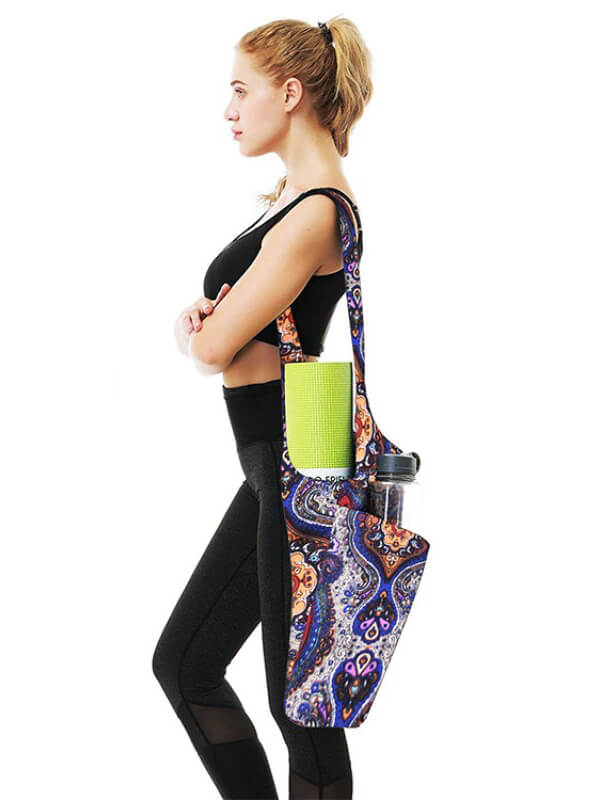 Fashion one-shoulder yoga bag with a colorful pattern, holding a yoga mat and water bottle, worn by a person wearing workout clothes.