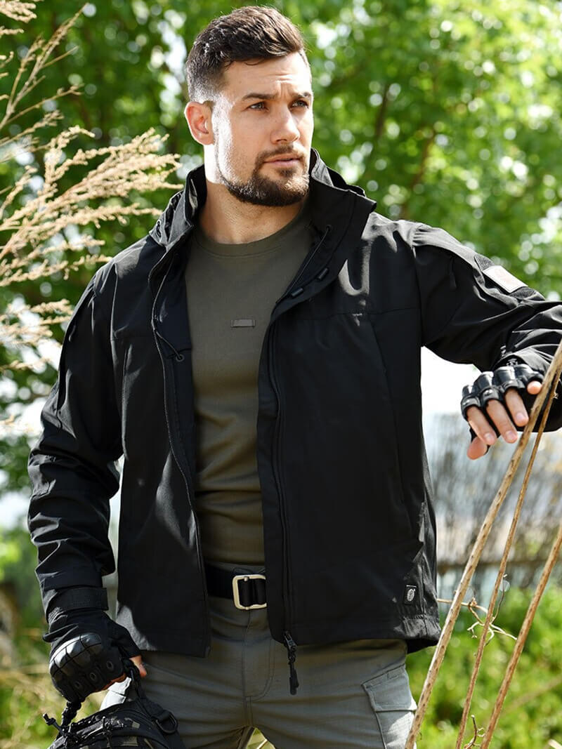 Man wearing black tactical jacket with hood for hunting outdoors.