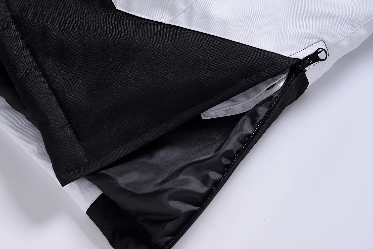 Close-up of black and white ski jacket with zip, highlighting waterproof material. Ideal for snowboarding and skiing adventures.