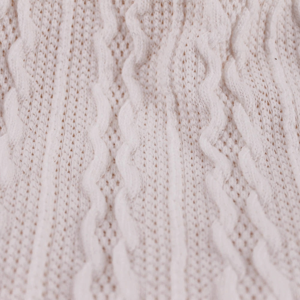 Close-up of a soft knit wool texture in neutral cream color, showing intricate cable patterns and cozy fabric design.
