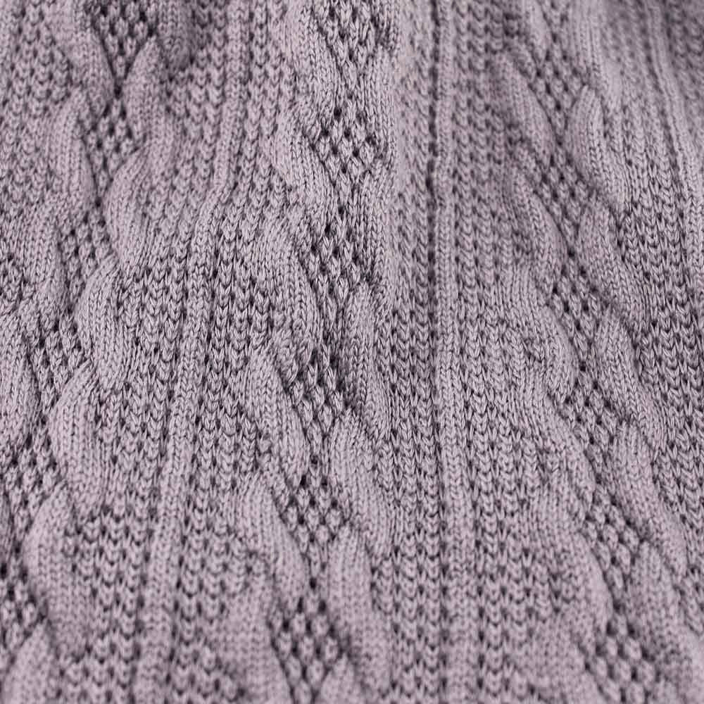 Close-up of a textured knit pattern on a soft gray hat, showcasing intricate cable design perfect for fashion and warmth.