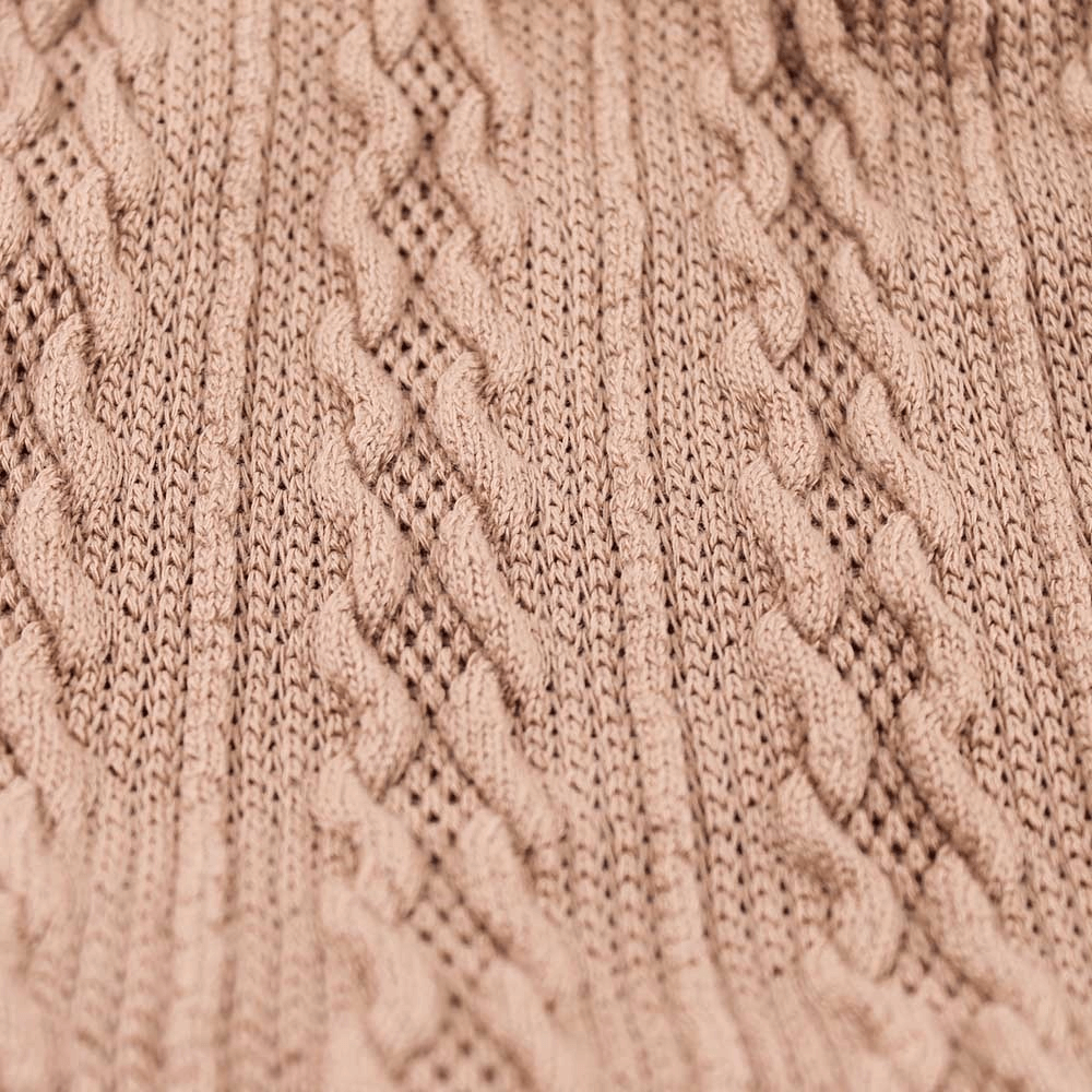 Close-up of a stylish soft knit pattern beanie fabric in beige showcasing intricate cable-knit design.