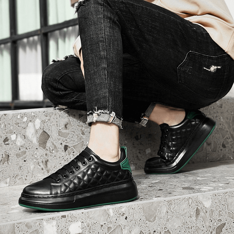 Fashionable black men's sneakers with quilted leather, worn casually with jeans, showcasing style and comfort on a modern staircase.