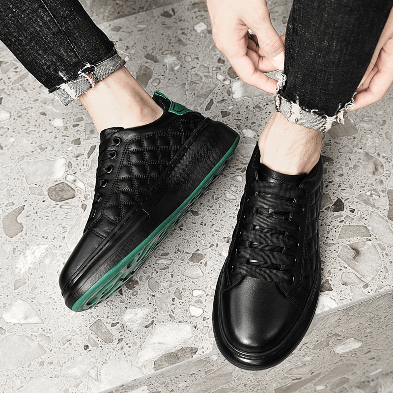Stylish men's sneakers with black leather uppers, green rubber soles, and elegant stitching, perfect for casual wear.