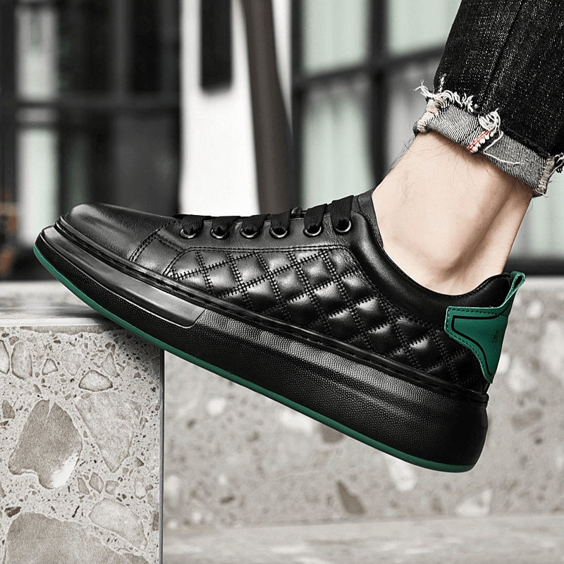 Black quilted men's sneaker with green accents on foot, featuring genuine leather and durable rubber sole for stylish comfort.