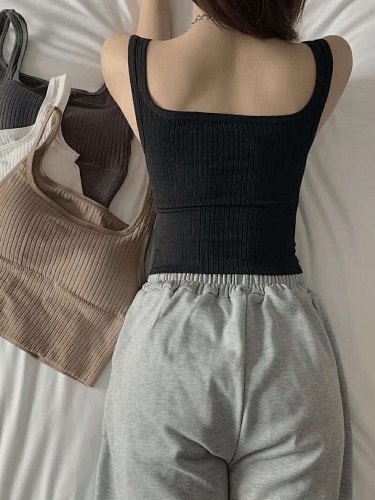 Fashionable black cropped sports women's top with straps, showcasing seamless design and breathable fabric for active comfort.