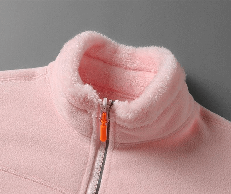 Close-up of stylish double-sided pink fleece jacket for women with cozy collar and zipper, made with thermal, windproof polyester and spandex.