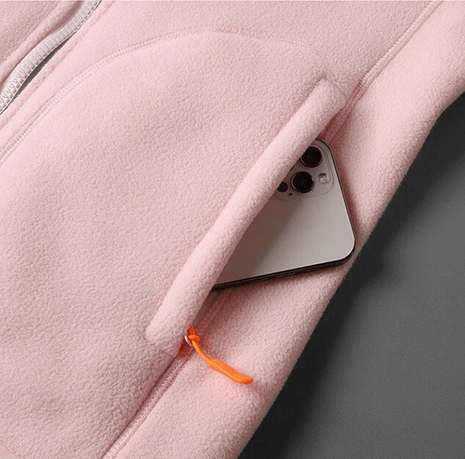 Close-up of pink fleece jacket pocket with zipper and smartphone inside, highlighting style and functionality for women.