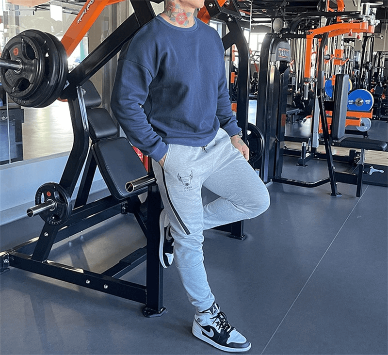 Man in a gym wearing a fashionable loose men's sweatshirt SF1114, showcasing casual sports style with O-neck and full sleeves.