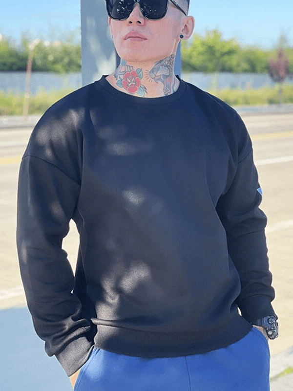 Man wearing Fashionable Loose Men's Sweatshirt SF1114 in black, standing outdoors in sunny weather.