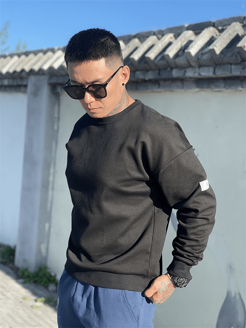 Fashionable loose men's black sweatshirt with O-neck, modeled outdoors; perfect stylish activewear for men, SF1114.