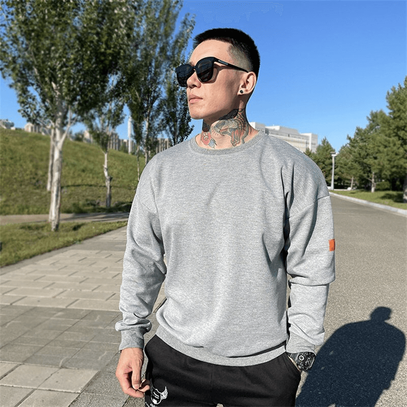 Man wearing a gray loose-fitting men's sweatshirt with O-neck collar outdoors, showcasing the stylish and comfortable activewear.
