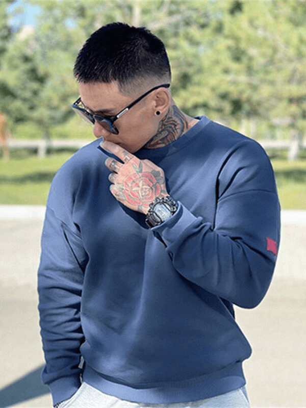 Stylish man wearing a fashionable blue loose men's sweatshirt or sports sweater outdoors, showcasing casual and cool activewear style.