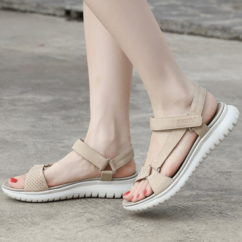 Woman wearing beige platform sandals with adjustable buckle strolling on sidewalk.