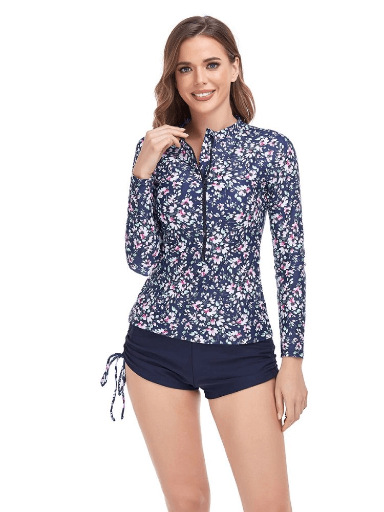 Woman wearing a fashionable two-piece swimsuit with long sleeves and floral print, featuring a stylish zipper. Ideal for sun protection.