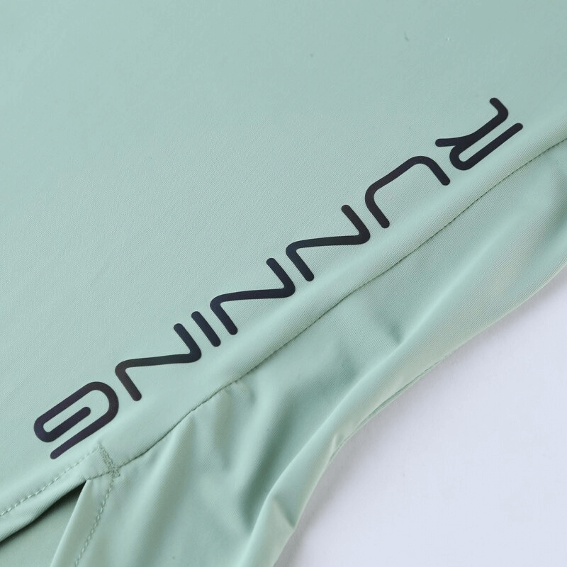 Close-up of a mint green women's sports asymmetrical t-shirt with 'RUNNING' text, featuring breathable fabric, perfect for workouts and yoga.
