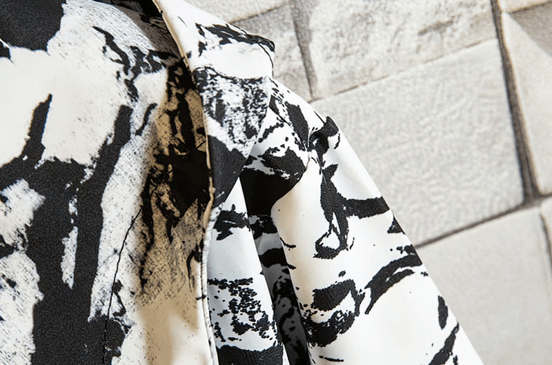 Close-up of printed fabric on female zipper hooded jacket, showing lightweight polyester material and abstract black and white design.
