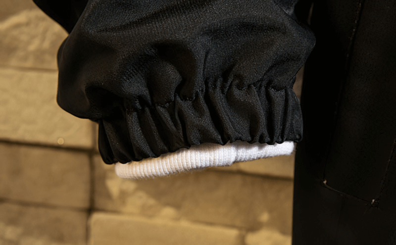 Close-up view of a black hooded jacket's sleeve, showing elastic cuff detail for a snug fit in lightweight windbreaker design.
