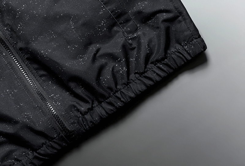 Close-up of a black zipper hooded jacket with subtle print, showcasing its lightweight polyester fabric and stylish design.
