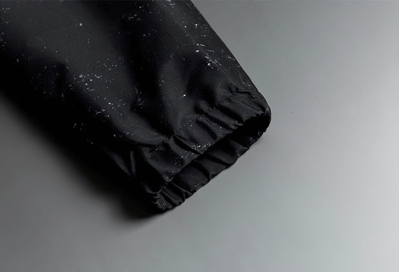 Close-up of black lightweight windbreaker sleeve with white print dots.