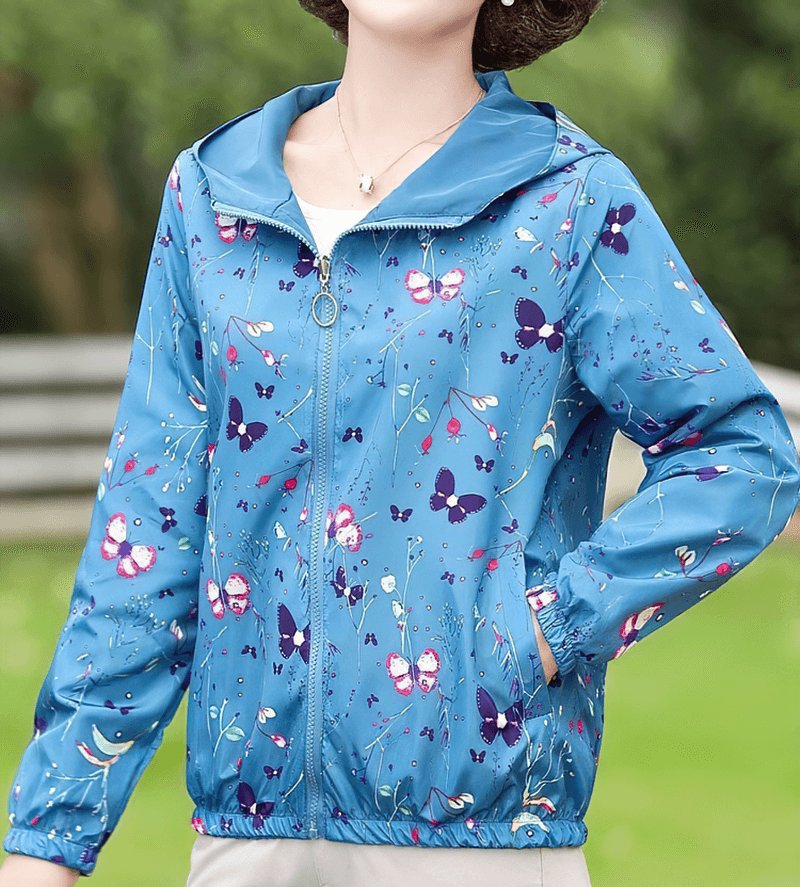 Female zipper hooded reversible windbreaker with floral print, featuring a blue fabric, pockets, and zipper closure.