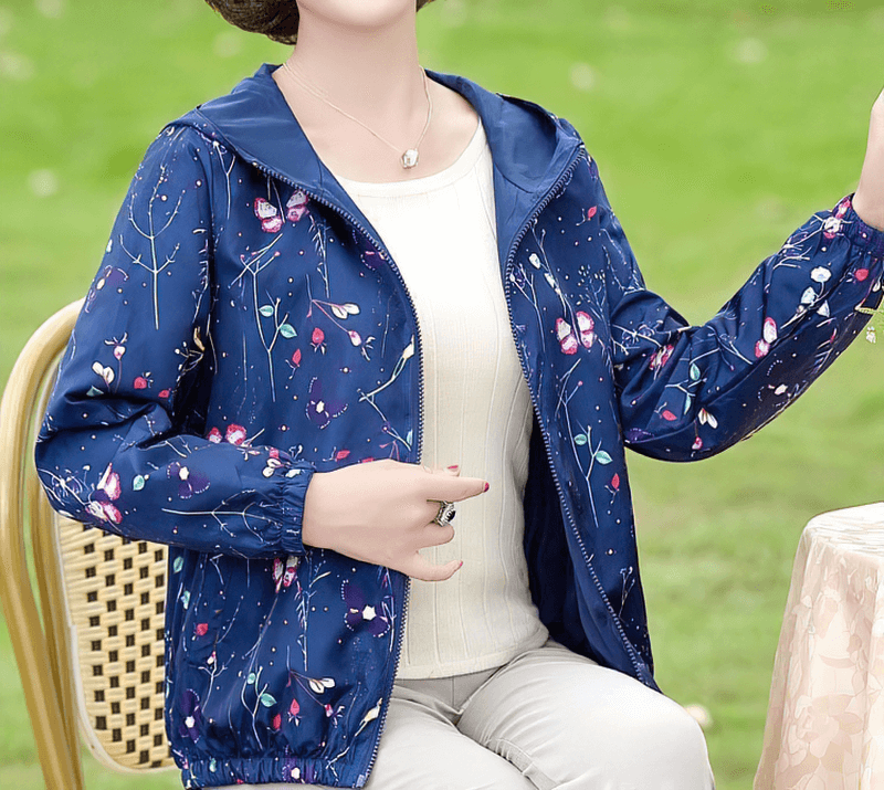 Female reversible floral windbreaker with hood and zipper, perfect for casual style and comfort, shown in a sitting pose outdoors.