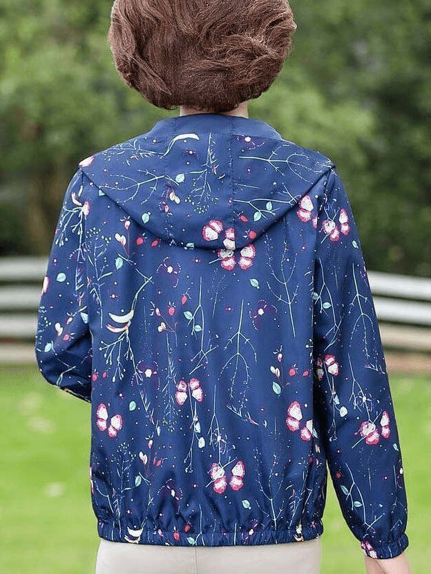 Model wearing a reversible floral print windbreaker with a hood, featuring a zipper and pockets, perfect for casual style and warmth.