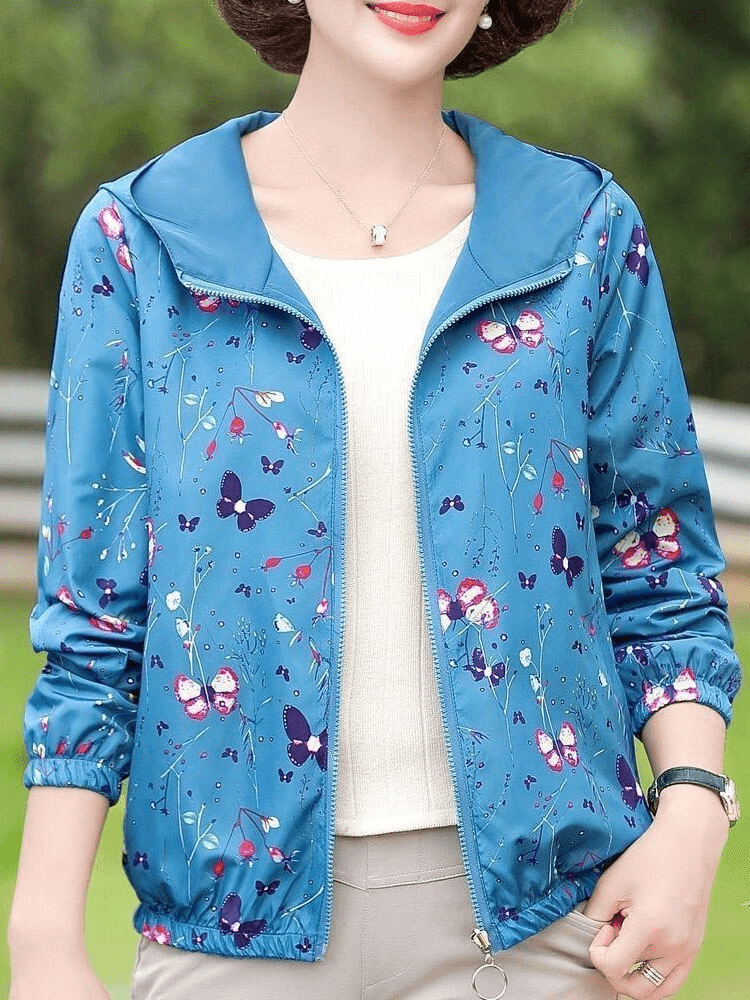 Woman wearing a blue floral print reversible windbreaker with zipper and hood, featuring casual style and pockets.