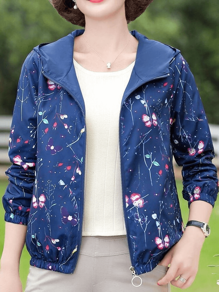 Woman wearing a blue floral print zipper hooded windbreaker, casual style with full sleeves and pockets.