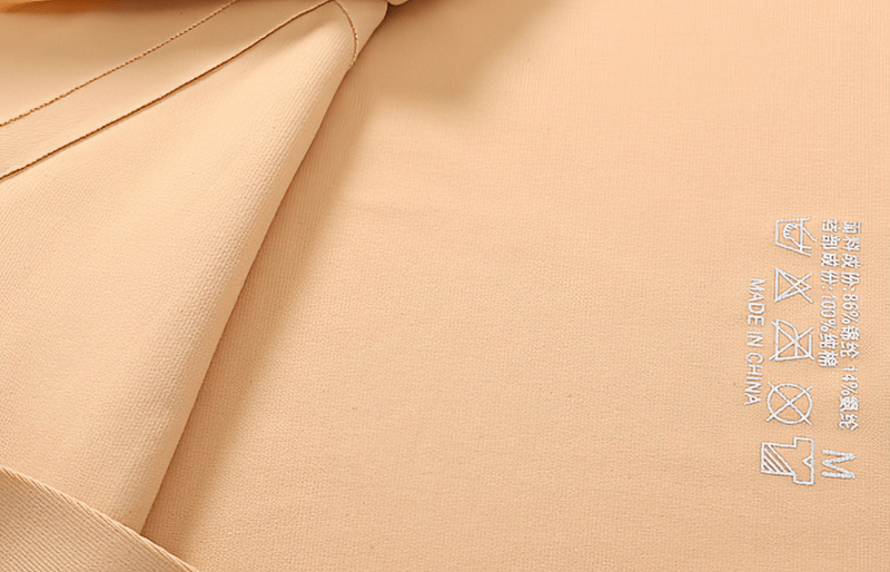 Close-up of solid color seamless briefs fabric in beige with care label symbols, showing soft texture and durability.