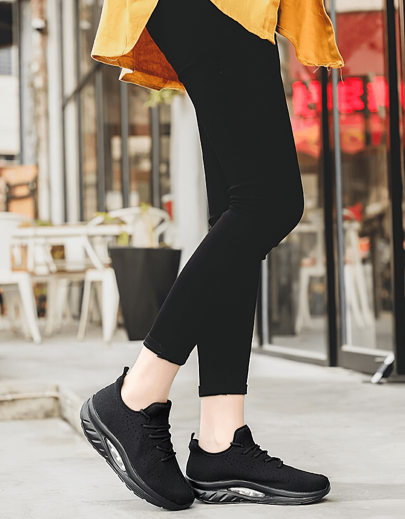 Woman wearing black Fitness Women's Lace-up Platform Sports Sneakers, SF0253, walking outside near a cafe.