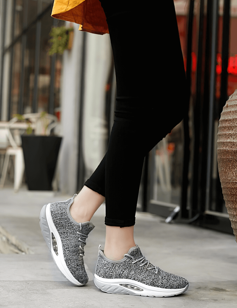 Woman wearing gray lace-up platform sports sneakers, perfect for fitness and lifestyle activities.