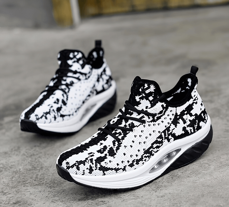 Black and white lace-up platform sports sneakers for women with breathable mesh upper on gray background.