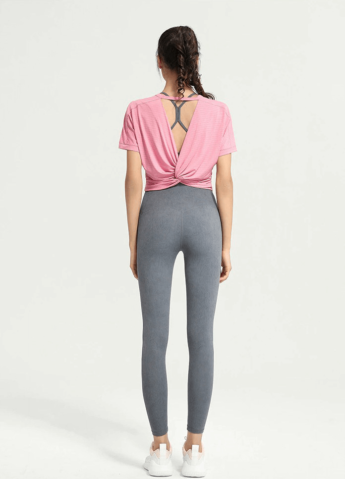 Back view of woman wearing pink backless gym crop top and gray leggings