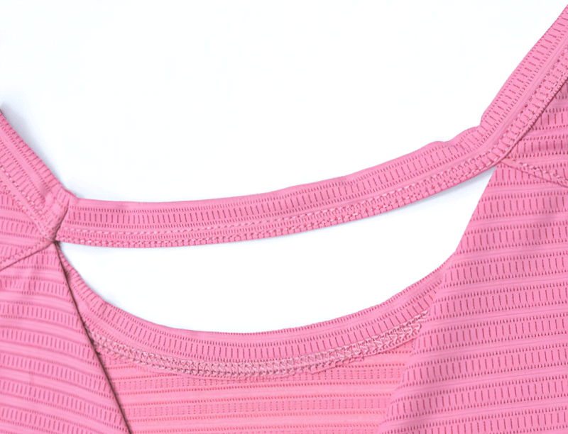 Close-up of a pink women's backless crop top fabric, highlighting the detailed texture and stitching, ideal for gym and fitness activities.