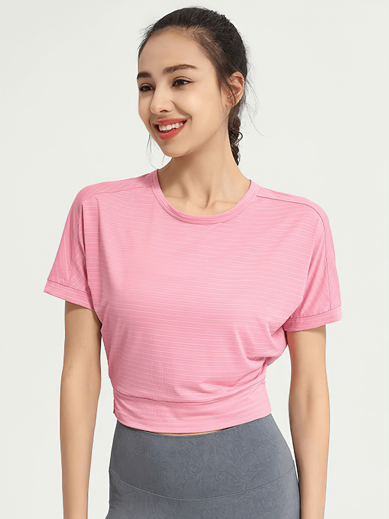 Smiling woman wearing a pink backless gym crop top and blue leggings, ideal for yoga and running. Stylish sportswear for active women.