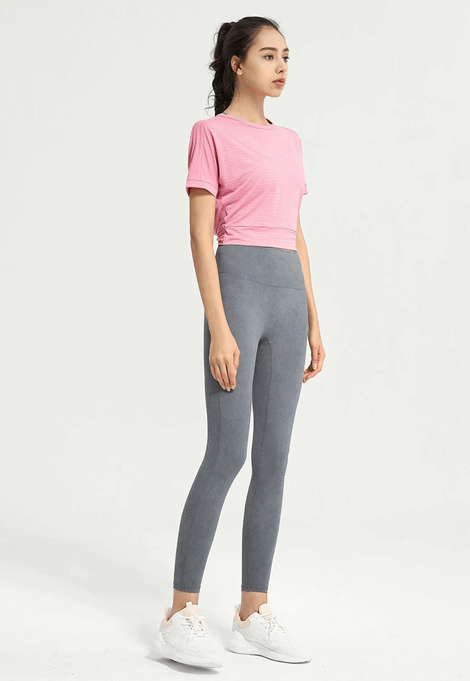 Woman wearing pink loose T-shirt and grey leggings, perfect for gym and yoga