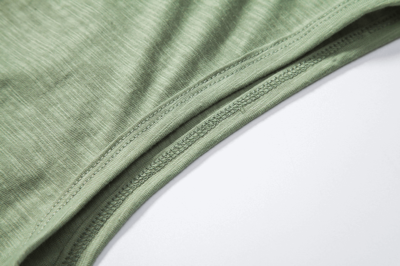 Close-up of green fabric detailing on a sleeveless hoodie, showcasing stitching and texture.
