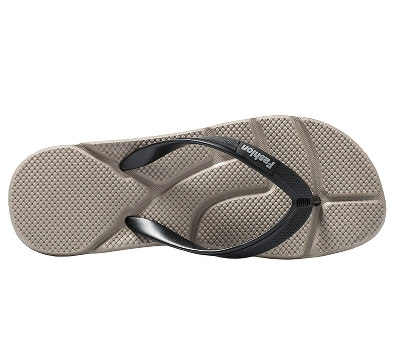 Bottom view of a beige flip flop with black strap, showcasing textured sole for comfort and support, perfect for beach and casual wear.