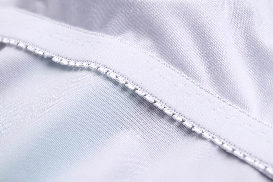 Close-up of white nylon-spandex fabric showcasing stitching and texture for durability in swimsuits.