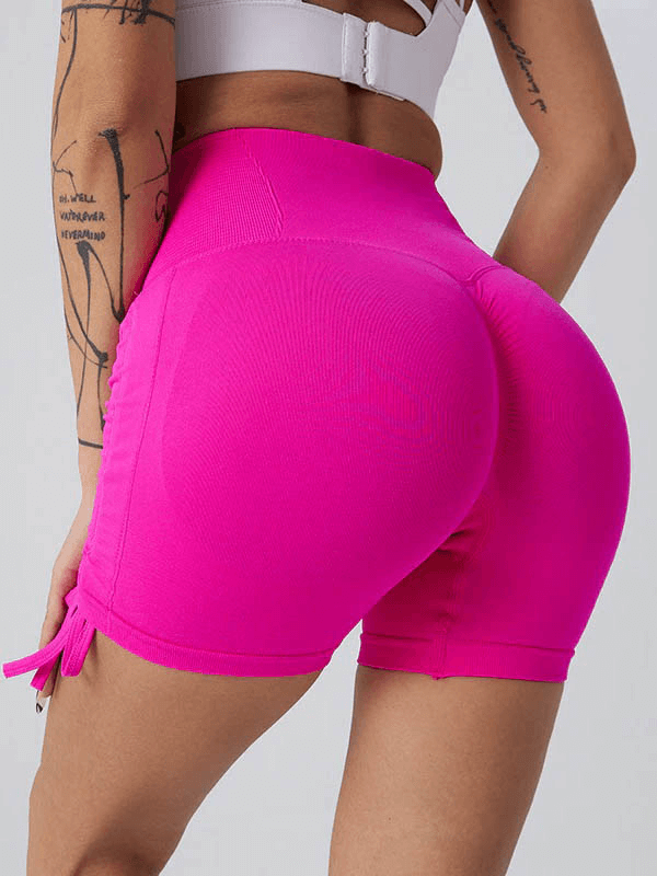 Woman wearing high waist pink sports shorts with drawstring, elastic waistband, and regular fit for yoga or everyday activities.