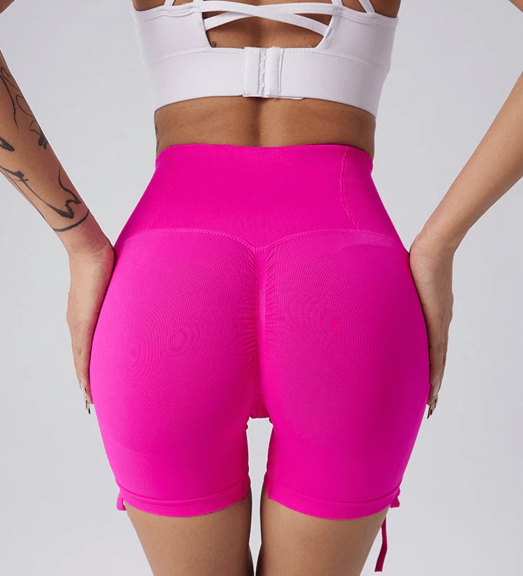 Woman wearing high waist pink sports shorts with drawstring and elastic waistband, ideal for yoga and fitness activities.