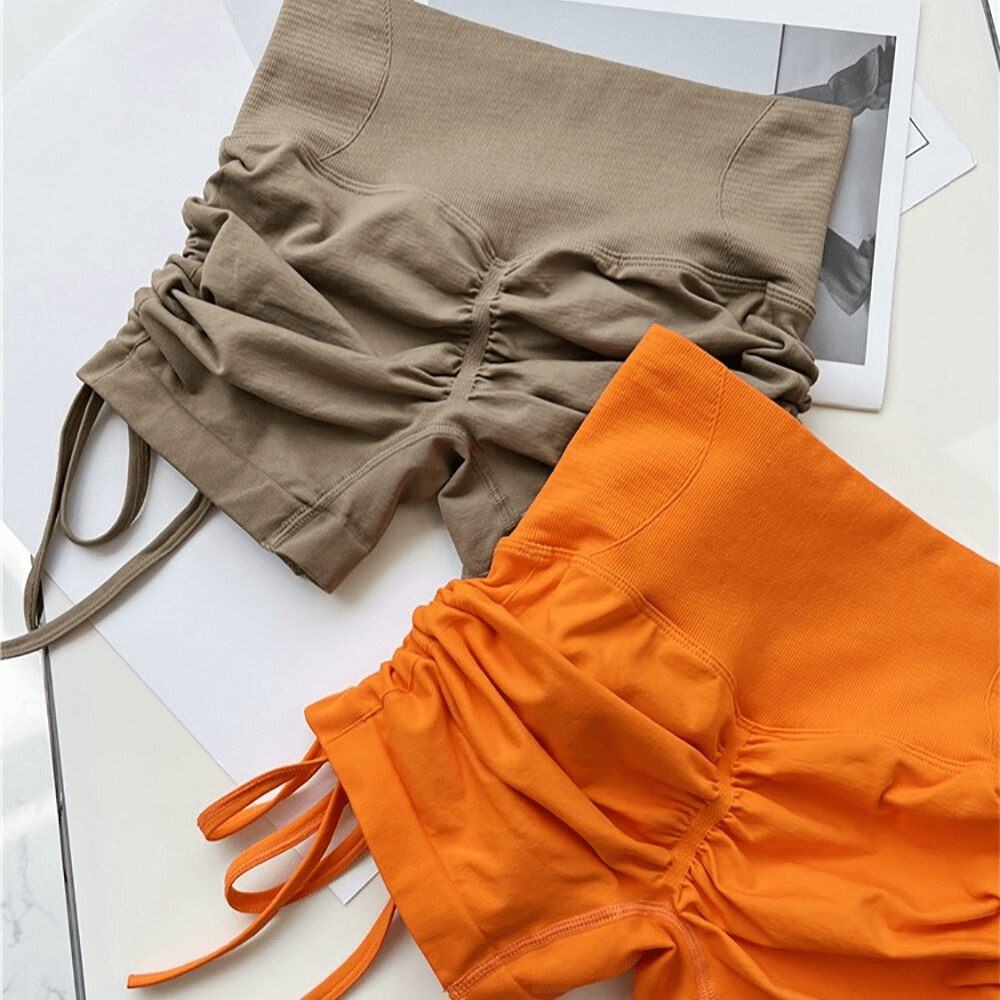 High waist drawstring sports elastic shorts for women in beige and orange, featuring elastic waistband and ruched detail.