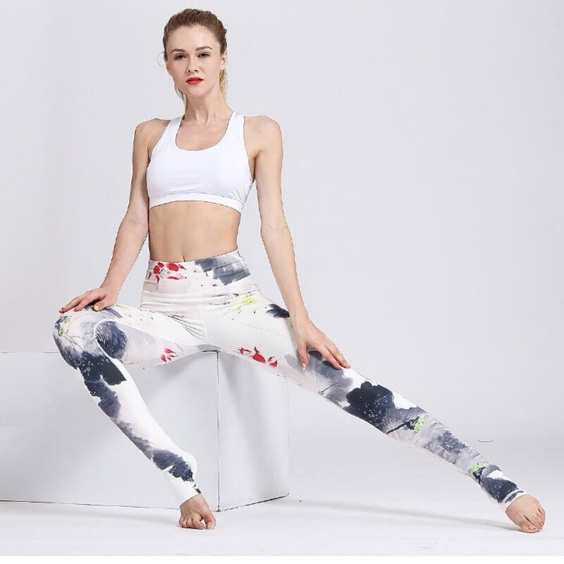 Woman wearing high-waist floral print sports leggings and white top, showcasing flexibility and performance in stylish activewear.
