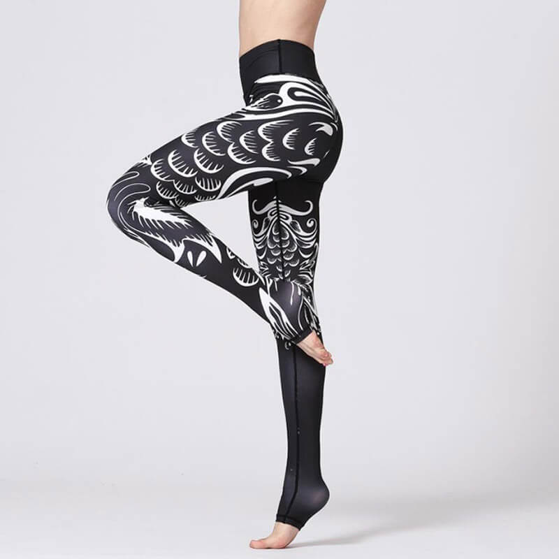 Woman wearing high waist sports leggings with floral prints, demonstrating flexibility and style on one leg.