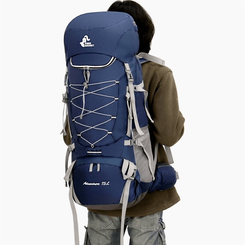 Hiker wearing large blue water-resistant backpack with rain cover, perfect for outdoor adventures.