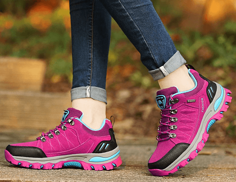 Woman wearing pink hiking shoes for women, SF0231, with durable rubber outsole and breathable lining, on an outdoor trail.